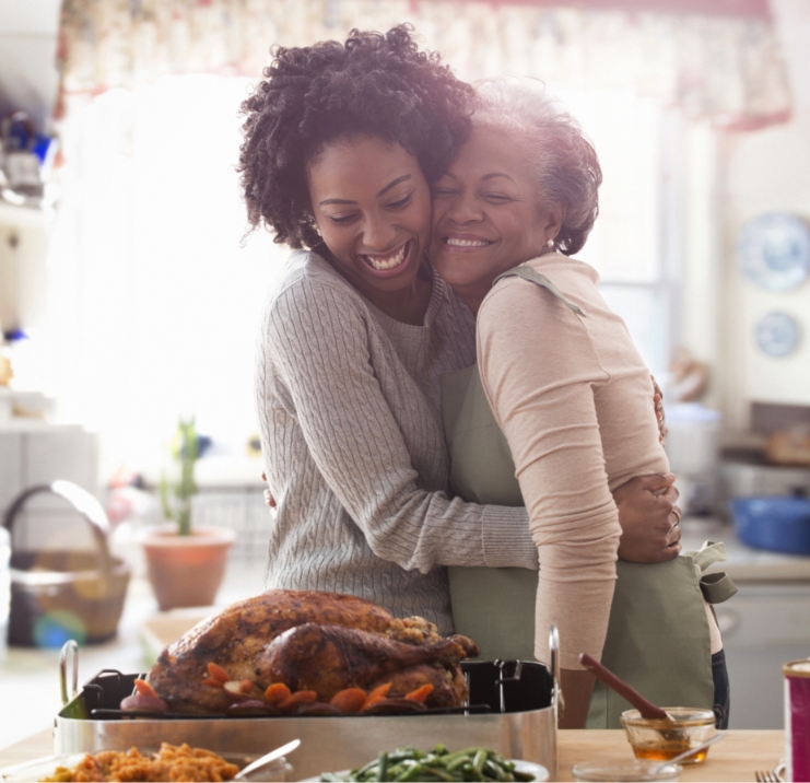 mother and daughter hugging and smiling in front of a meal