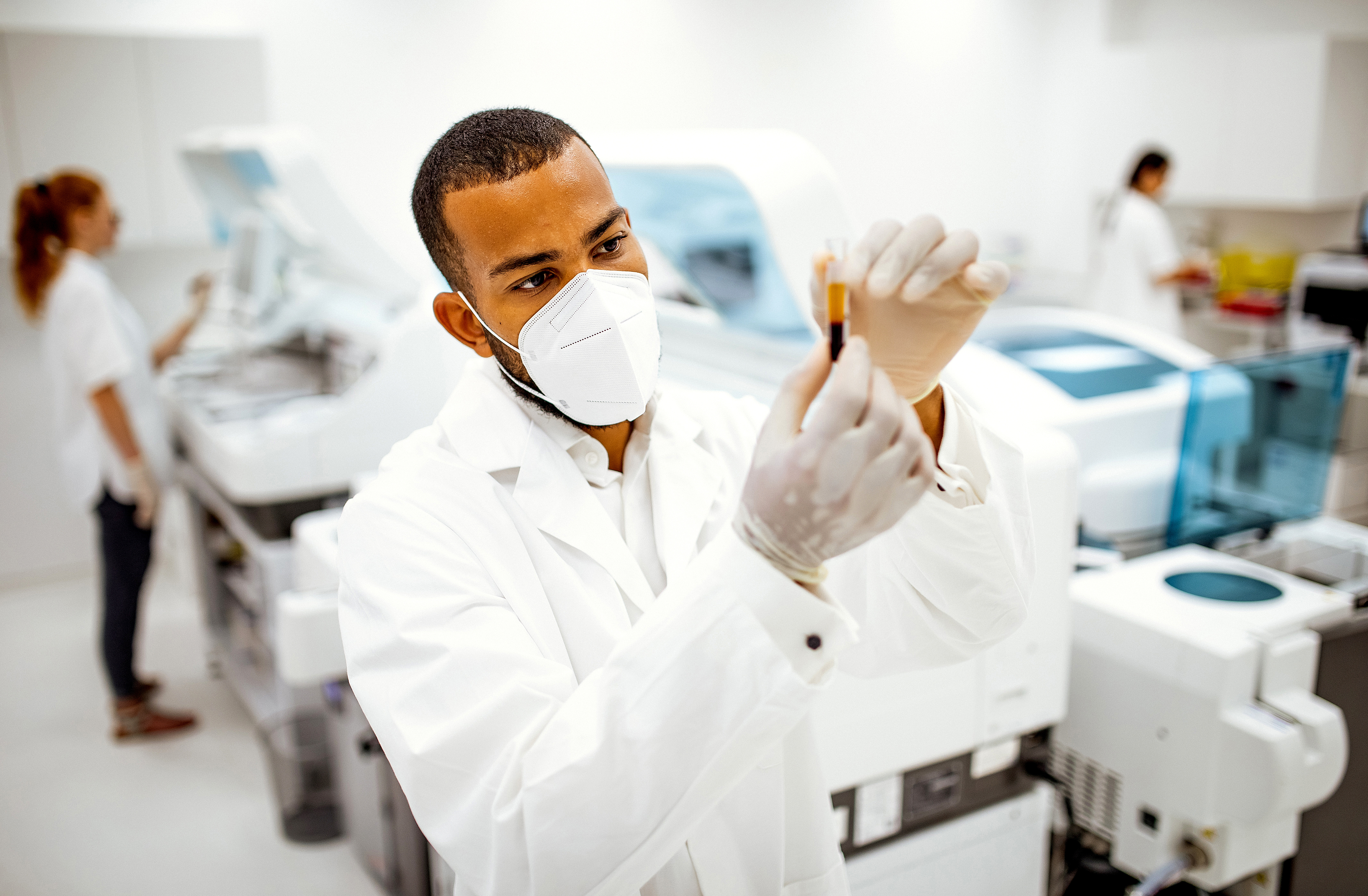 man in lab examining vial of fluid